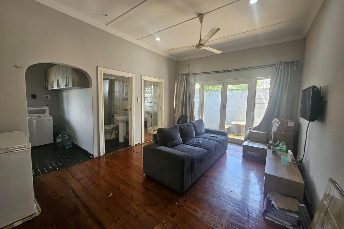 A living room featuring polished timber flooring, a ceiling fan, and direct access to an outdoor patio area through glass doors.
