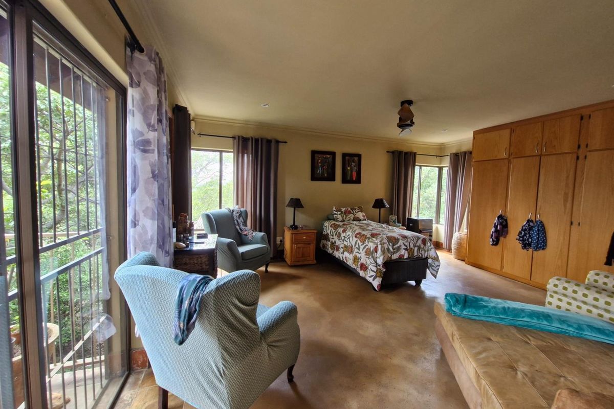 Spacious bedroom featuring built-in wooden cupboards, polished concrete flooring, and large sliding glass doors providing access to an outdoor balcony area.