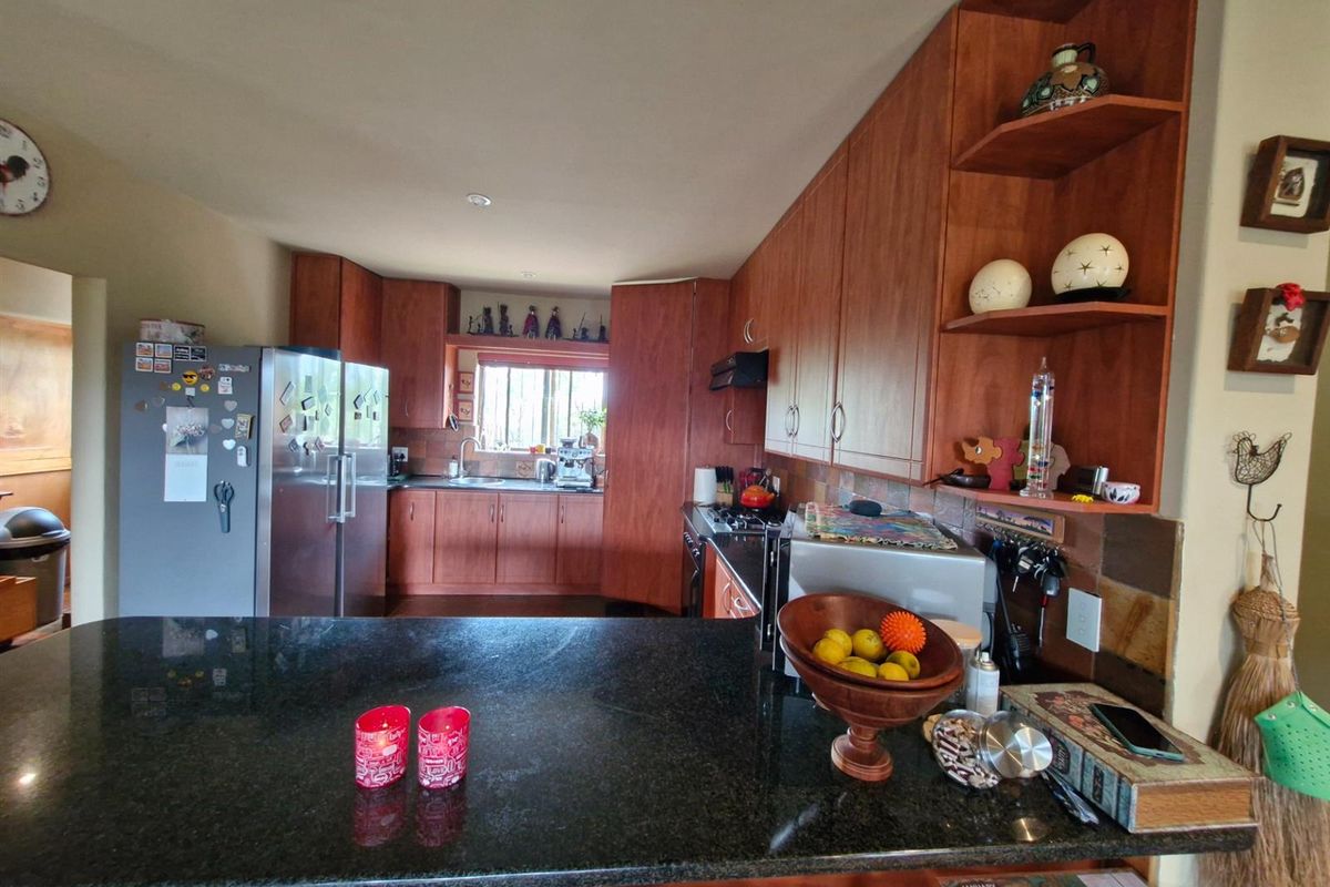A functional kitchen featuring dark granite countertops, wood-veneer cabinetry, and an integrated breakfast bar, providing ample workspace and storage.