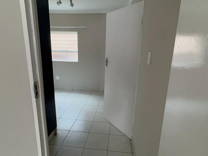 An empty bedroom featuring tiled flooring and neutral wall finishes, offering a blank canvas for personalization.