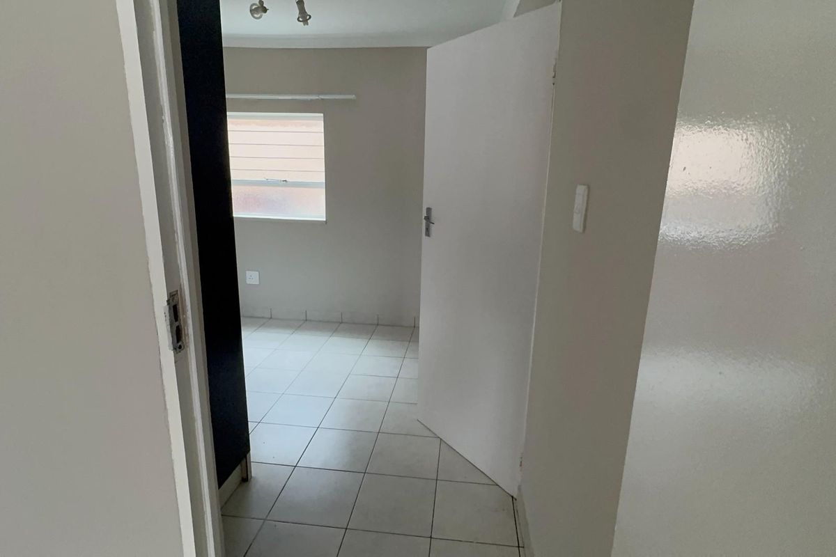 An empty bedroom featuring tiled flooring and neutral wall finishes, offering a blank canvas for personalization.