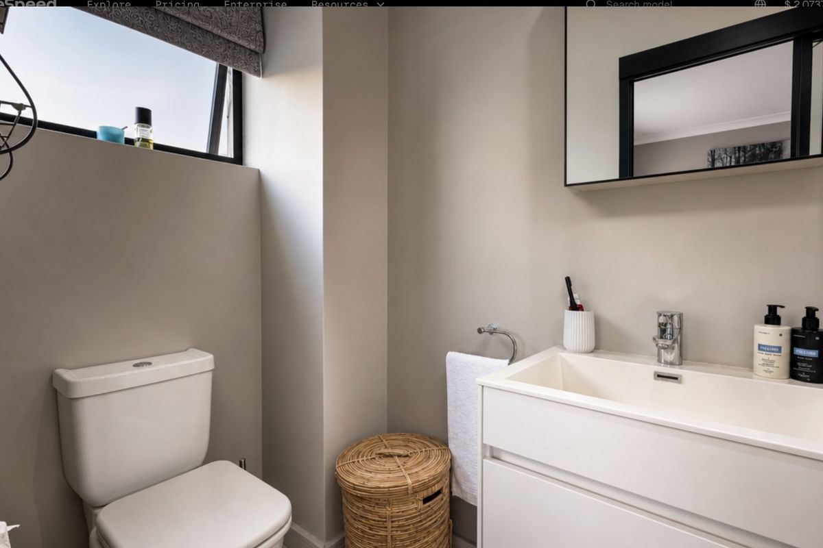 A modern, well-maintained bathroom featuring a sleek vanity unit, basin with mixer tap, wall-mounted mirror, and a functional awning window for natural light.