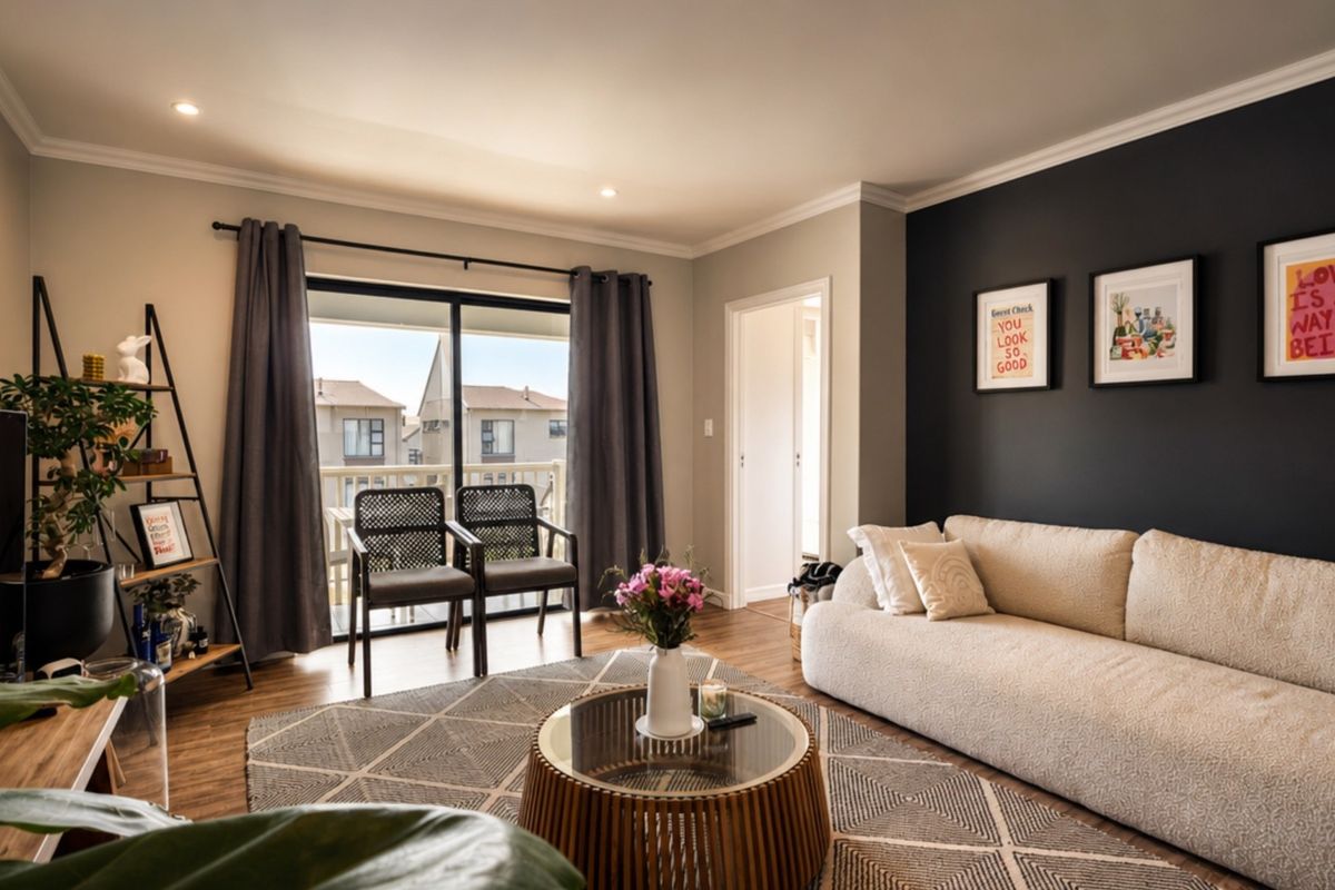 A well-maintained living room featuring laminate flooring, recessed lighting, crown molding, and a sliding glass door providing access to an outdoor balcony.