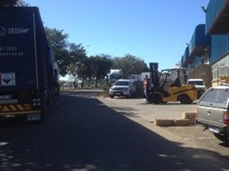 Exterior view of the industrial property yard, featuring paved access areas and building facade with loading bay access.