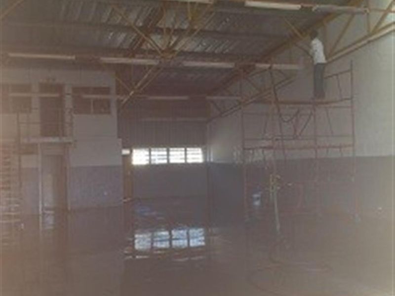 Spacious industrial warehouse unit featuring high ceilings, exposed steel trusses, polished concrete flooring, and an integrated mezzanine office area.