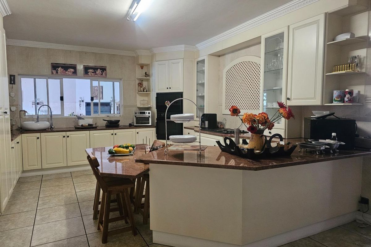 Spacious kitchen featuring granite countertops, cream-colored cabinetry, integrated oven, and a central island with breakfast bar seating.