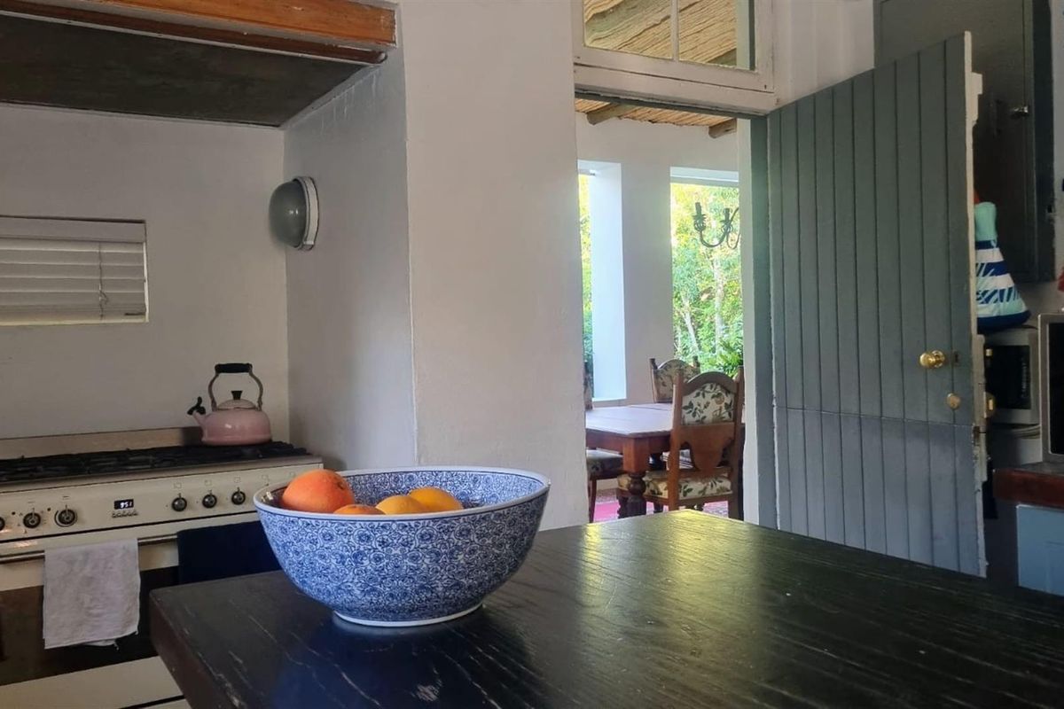 A view from the kitchen looking towards an outdoor dining area, featuring a built-in stove and traditional cabinetry.