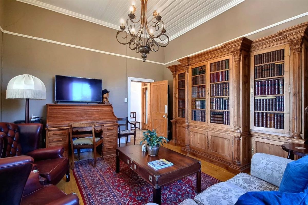 A classic living room featuring high ceilings, ornate crown molding, and a large, built-in wooden library bookcase.