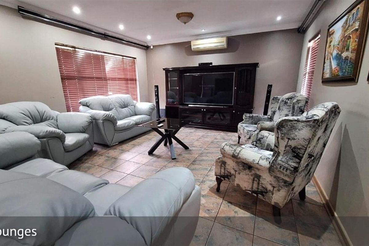 A spacious living room featuring tiled flooring, recessed ceiling lighting, and a wall-mounted air conditioning unit.