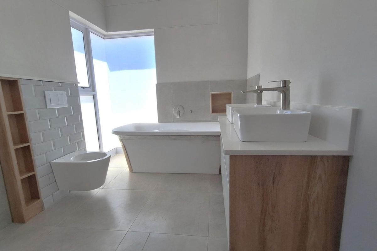 Modern bathroom featuring a freestanding bathtub, wall-mounted toilet, and double vanity with vessel sinks and wood-look cabinetry.