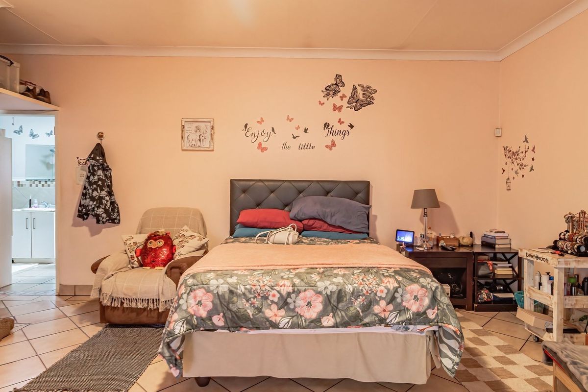 A bedroom featuring tiled flooring, coving, and a built-in cupboard, with a view into an adjacent room.