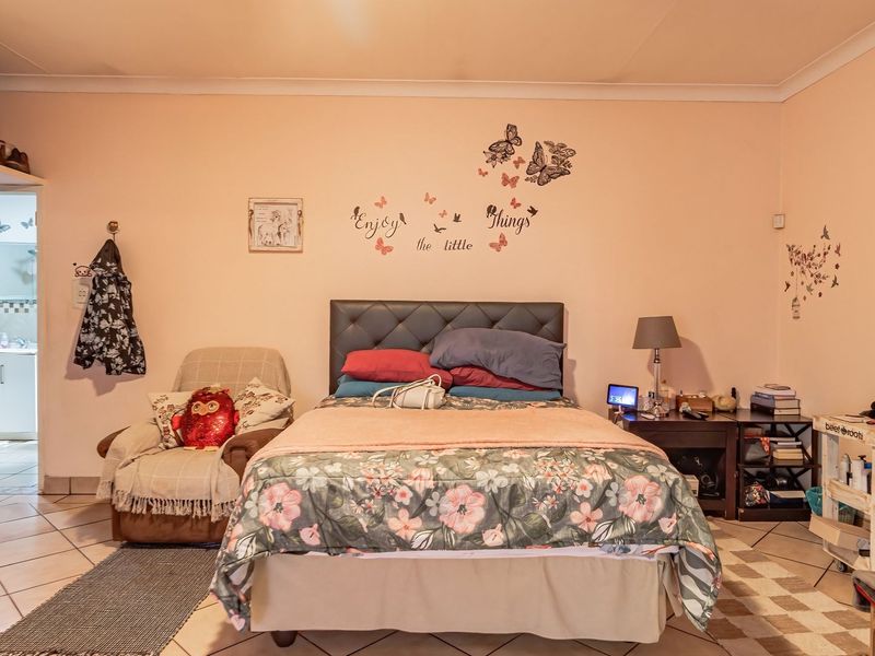 A bedroom featuring tiled flooring, coving, and a built-in cupboard, with a view into an adjacent room.