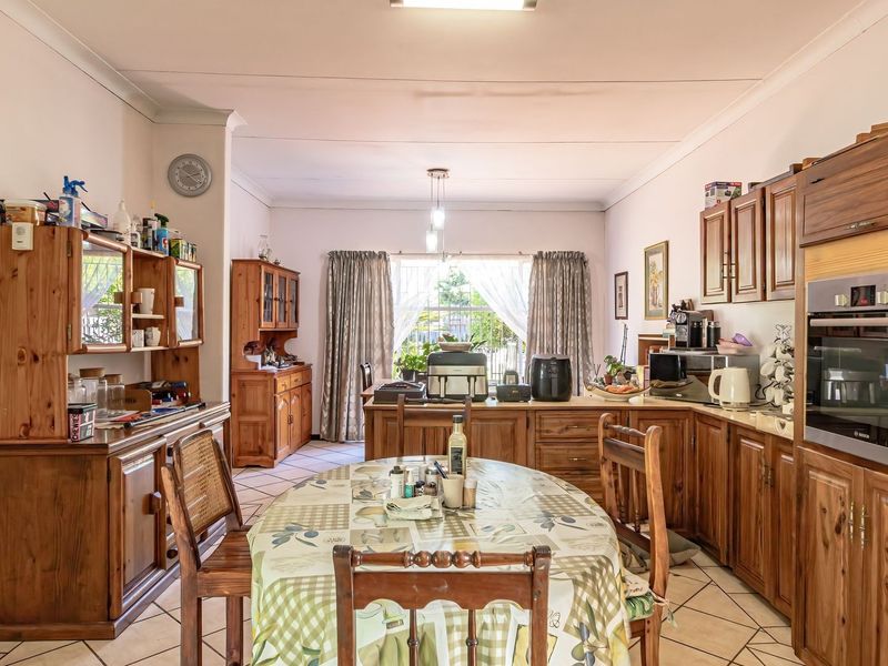 Open-plan kitchen and dining area featuring traditional wooden cabinetry, built-in oven, and tiled flooring, offering a functional layout with direct access to the garden.