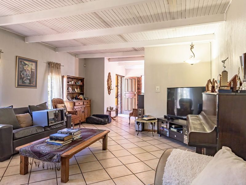 Spacious living room featuring exposed beam ceilings and neutral tiled flooring, providing a comfortable and functional area for relaxation.