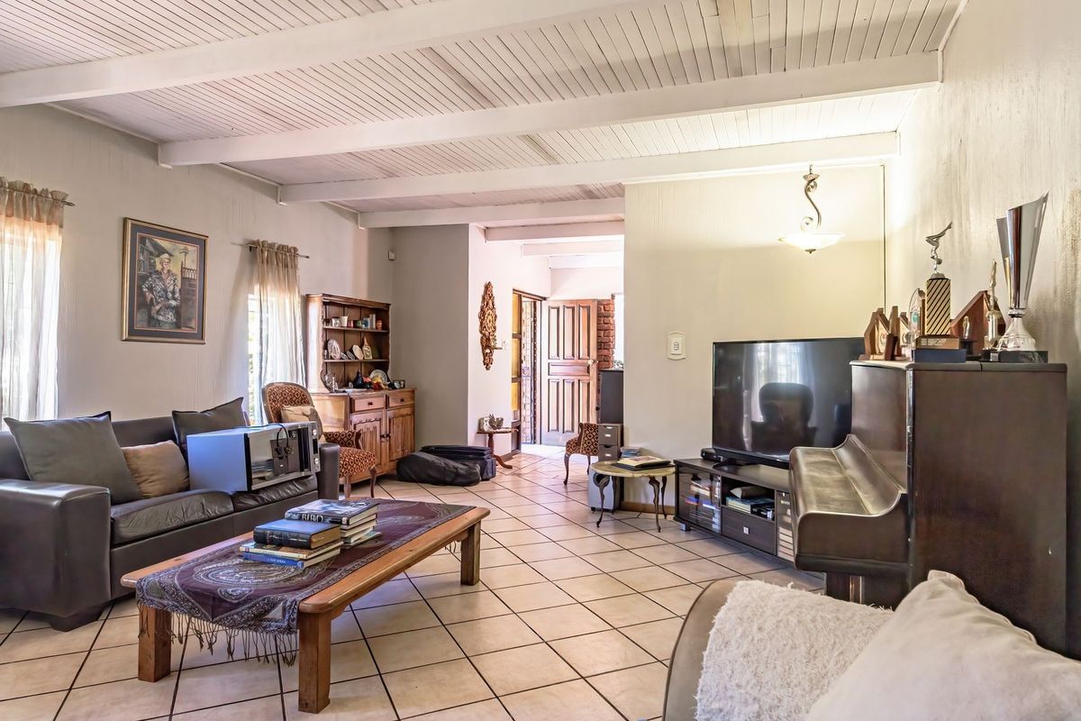 Spacious living room featuring exposed beam ceilings and neutral tiled flooring, providing a comfortable and functional area for relaxation.