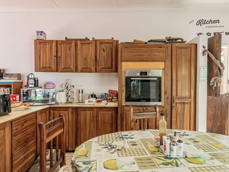 A functional kitchen featuring traditional wooden cabinetry, built-in oven, and ample counter space, offering a classic aesthetic with potential for modern updates.