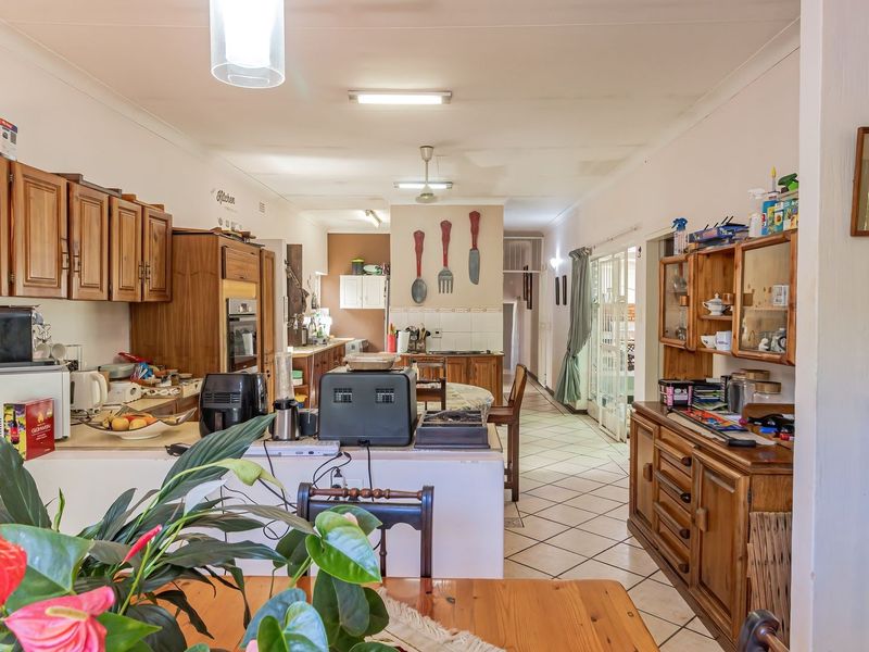 Open-plan kitchen and dining area featuring traditional wooden cabinetry, tiled flooring, and a functional layout with integrated storage solutions.