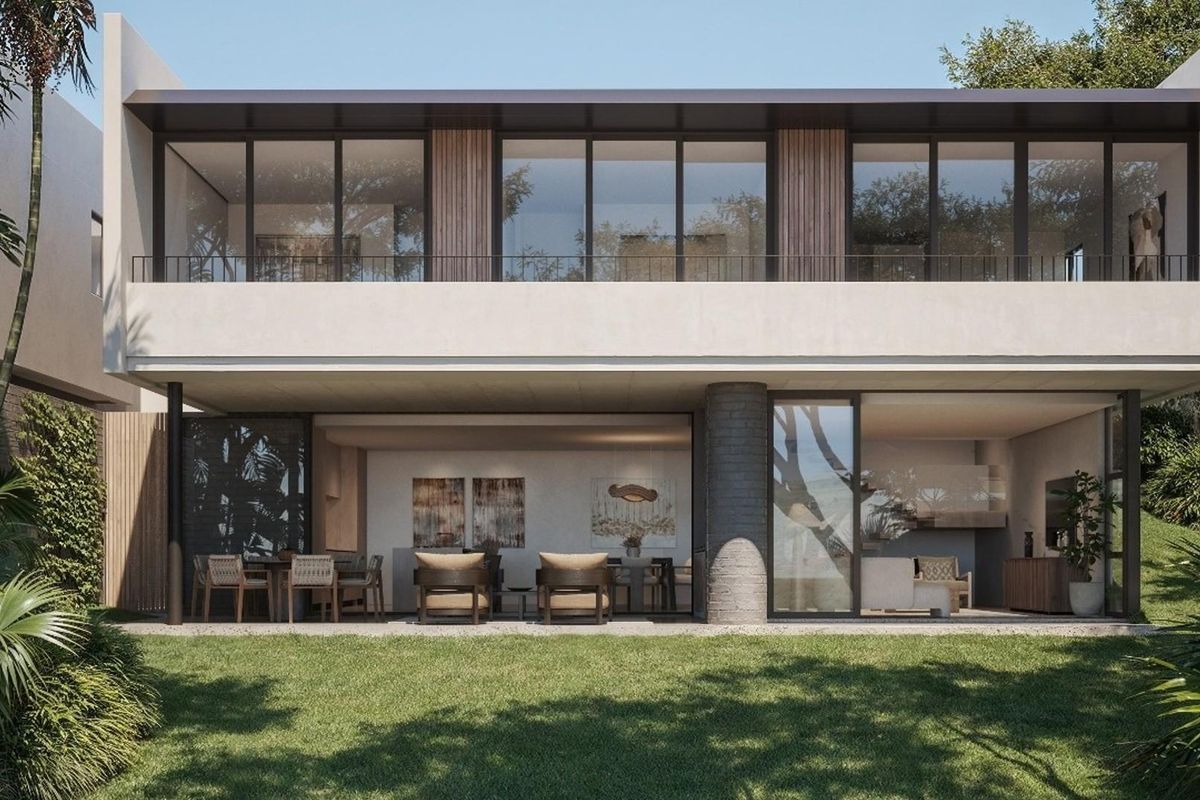 A modern two-story residential exterior featuring a spacious ground-floor patio, large glass sliding doors, and a balcony overlooking a landscaped garden.