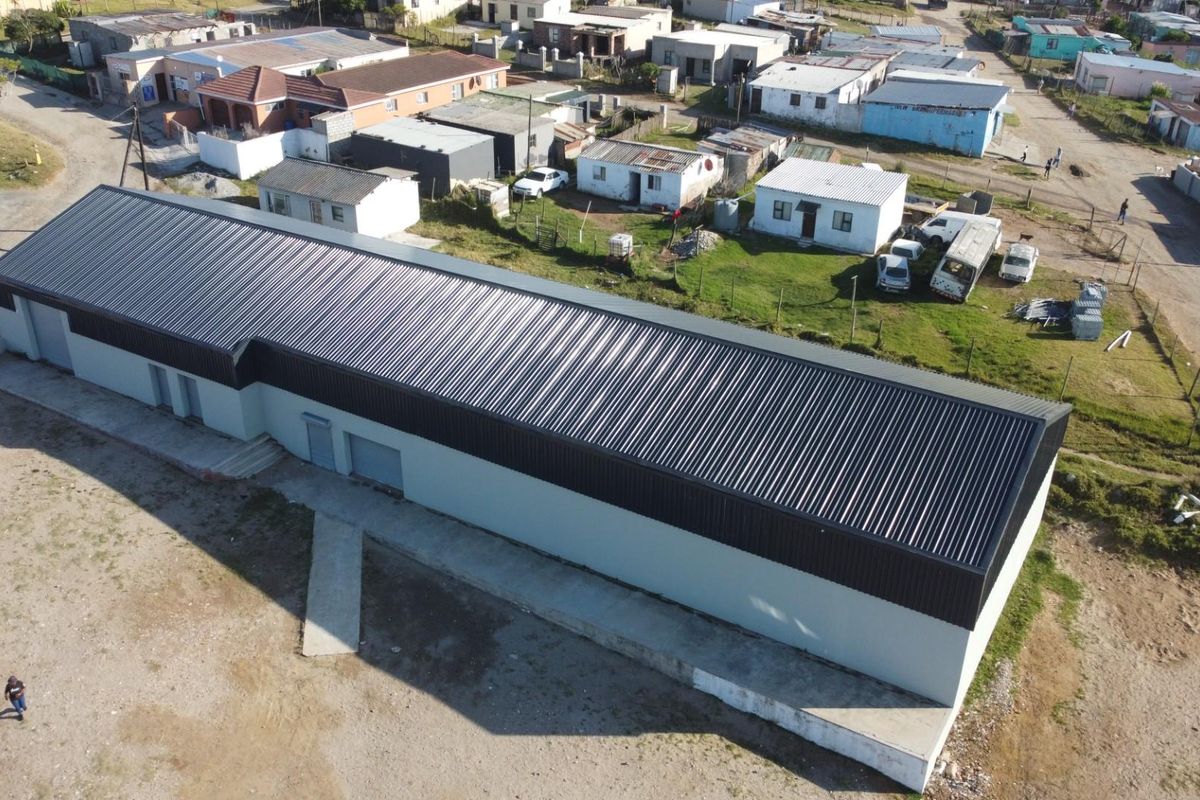 Aerial view of a large rectangular retail or warehouse building featuring a modern corrugated metal roof and concrete foundation in a residential area.