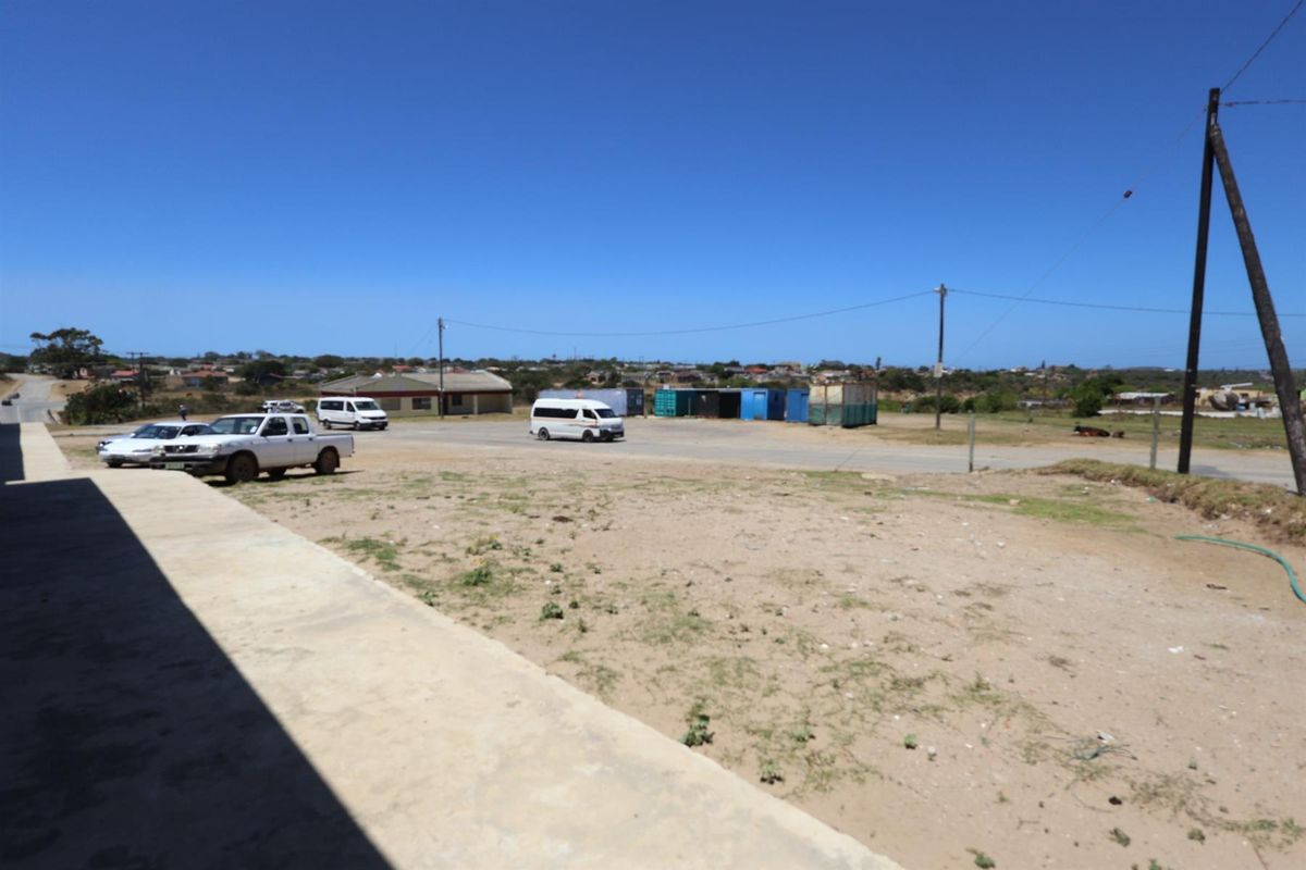An exterior view of the property grounds showing an unpaved open area with a concrete walkway and surrounding street access.