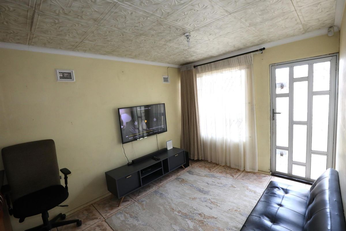 A living room featuring tiled flooring, a textured ceiling, and a security door leading to the exterior.