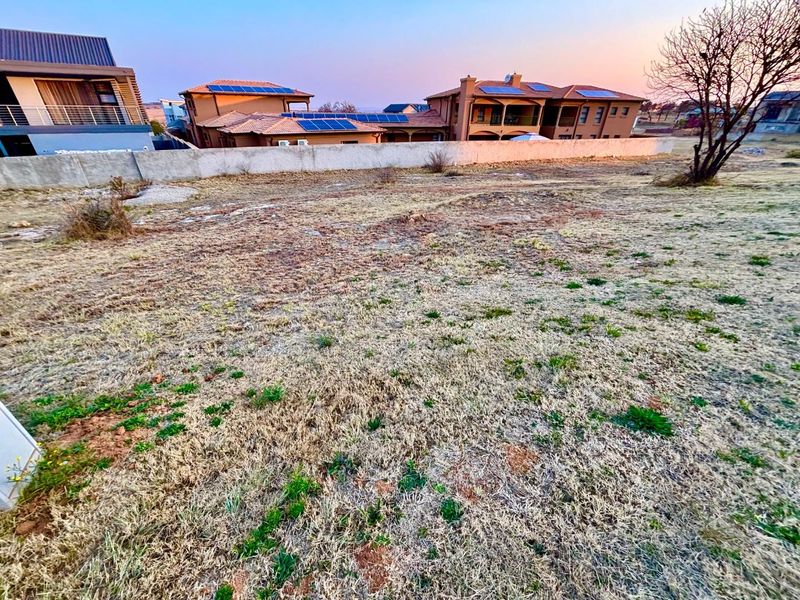 A vacant residential plot featuring a boundary wall, offering a clear space for potential development within an established neighborhood.