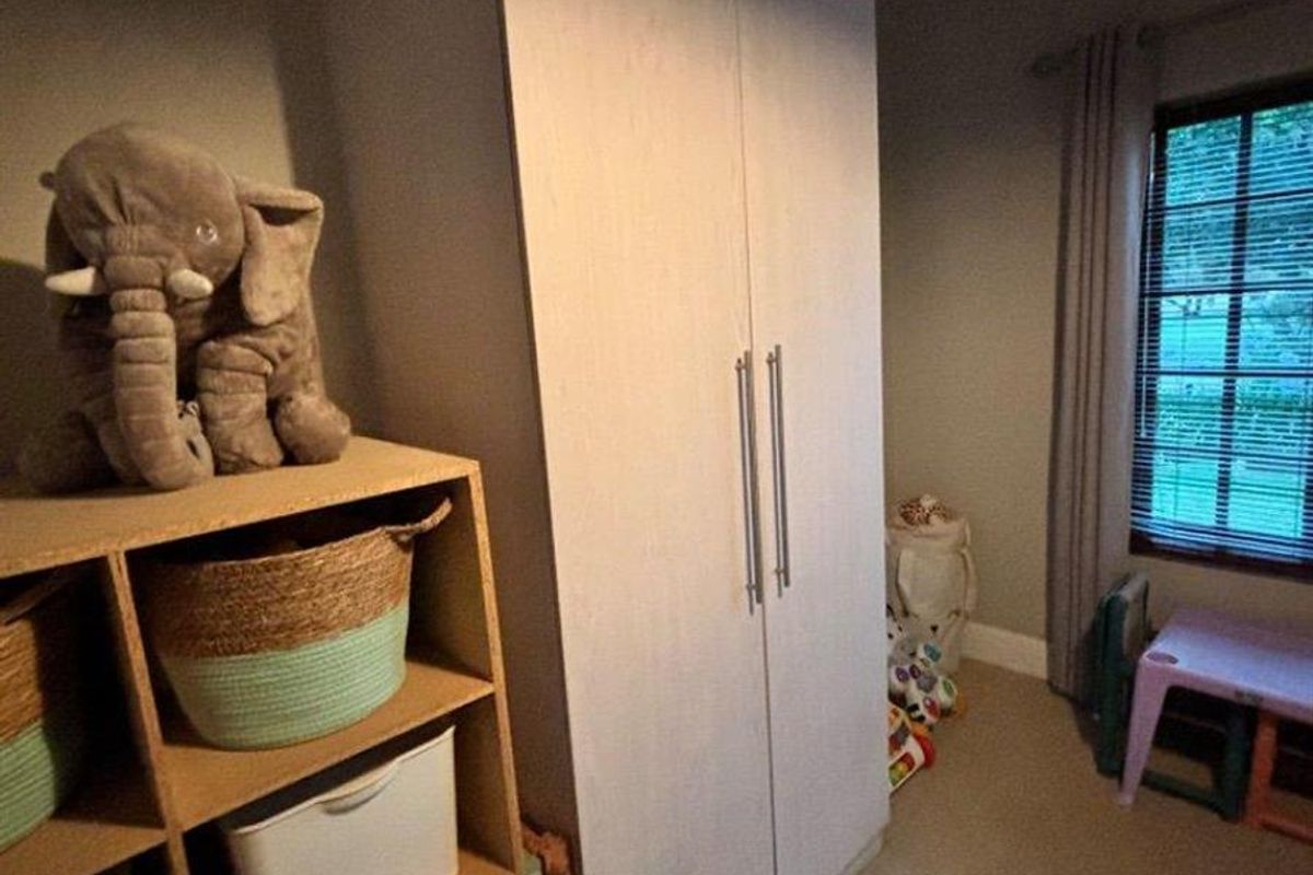 A bedroom featuring a built-in wardrobe and window blinds, currently used as a children's play area.