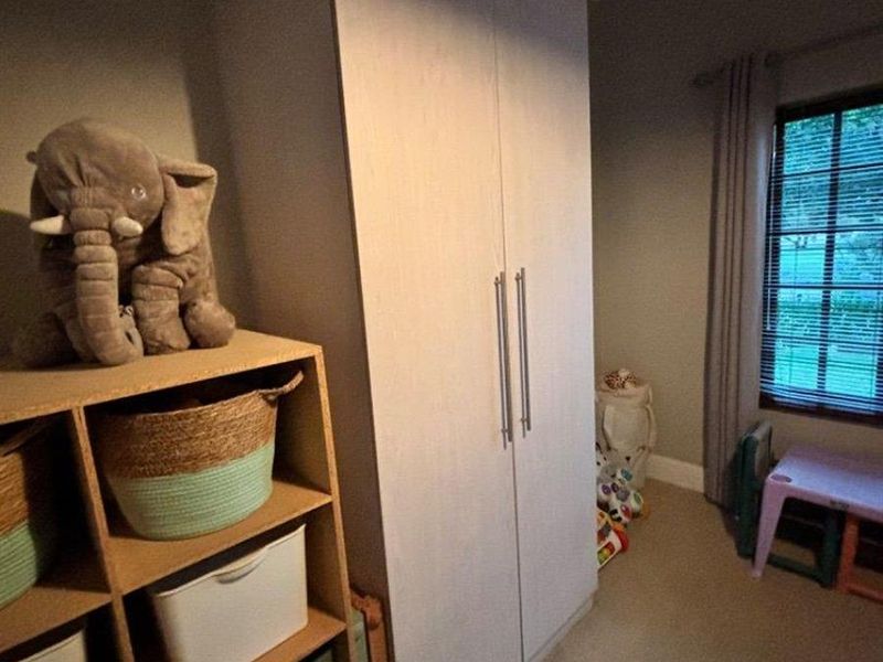 A bedroom featuring a built-in wardrobe and window blinds, currently used as a children's play area.