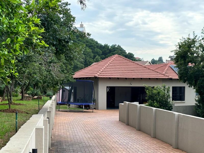 A view of the property's front exterior, featuring a paved driveway, concrete boundary walls, and a tiled roof garage structure.