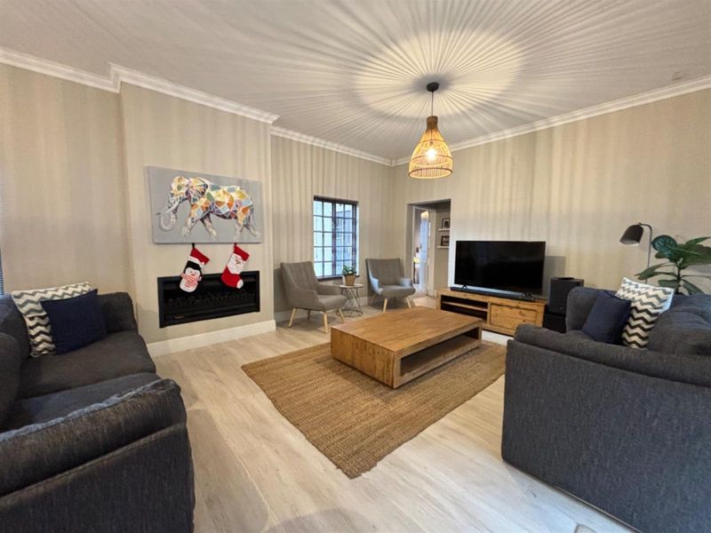 A well-maintained living room featuring a built-in fireplace, crown molding, and light-toned laminate flooring, creating a comfortable and inviting atmosphere.