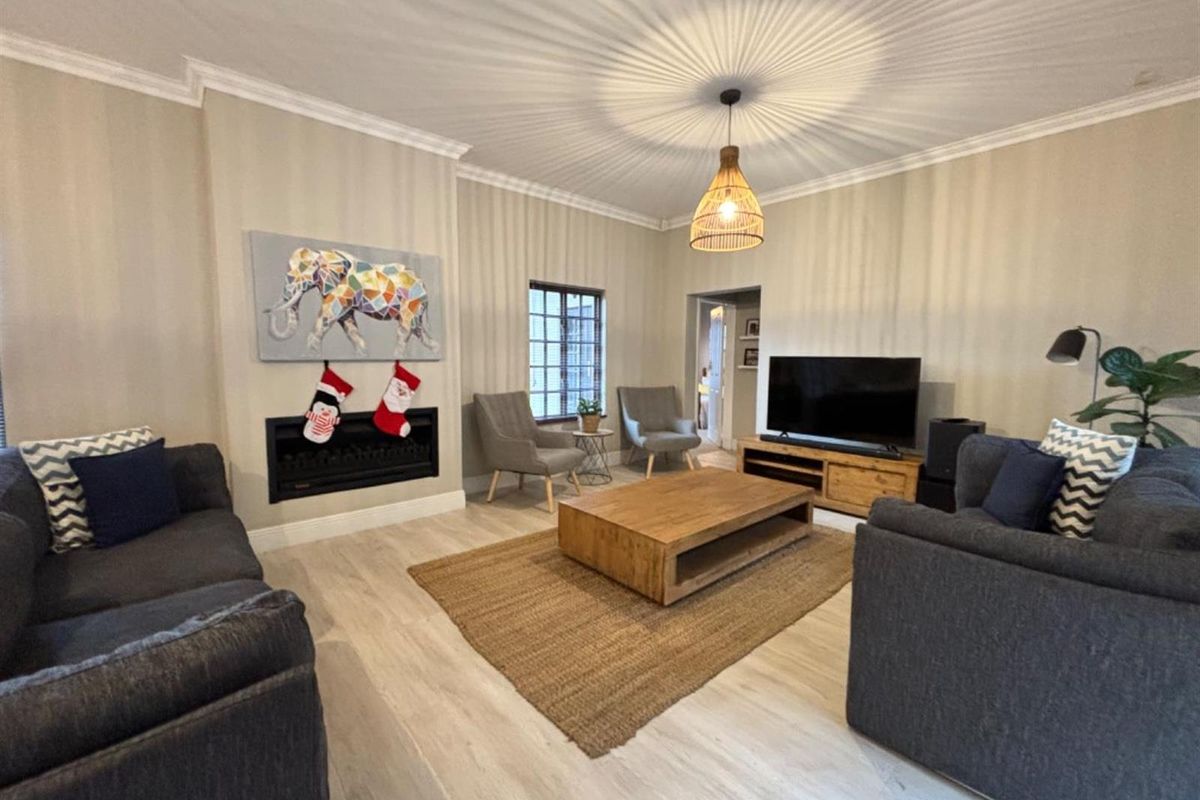 A well-maintained living room featuring a built-in fireplace, crown molding, and light-toned laminate flooring, creating a comfortable and inviting atmosphere.
