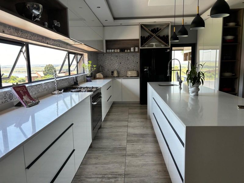 Modern kitchen featuring a large central island, quartz countertops, gas stove, and integrated wine storage with expansive views through a wide horizontal window.