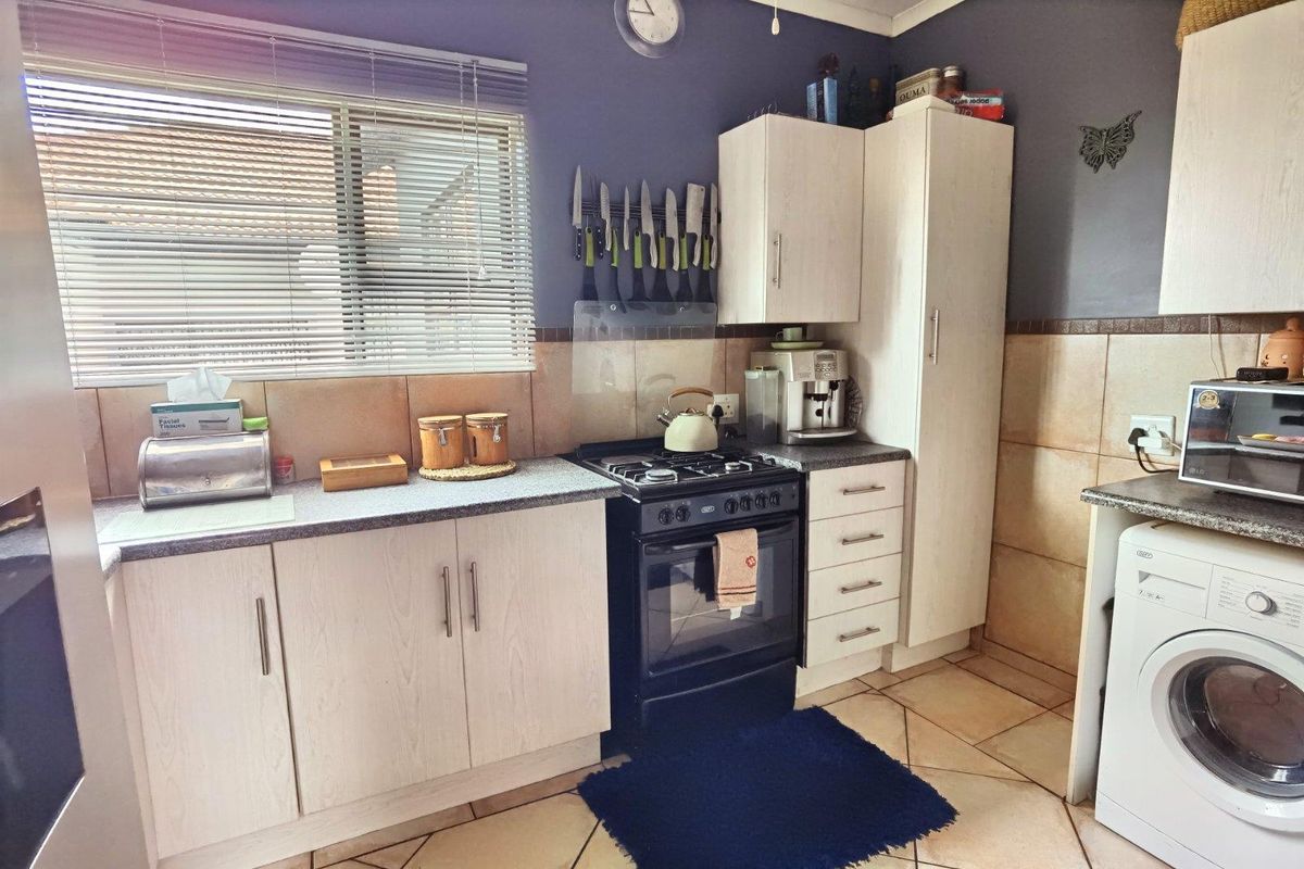 A functional kitchen featuring light-toned laminate cabinetry, stone-look countertops, a gas stove with oven, and tiled flooring with a neutral backsplash.
