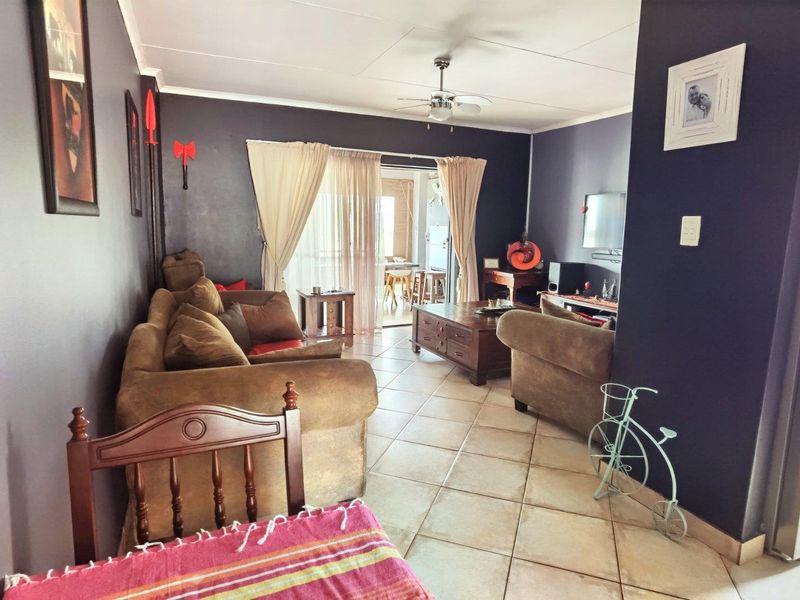 Spacious living room featuring tiled flooring, a ceiling fan, and sliding glass doors that provide access to an outdoor patio area.