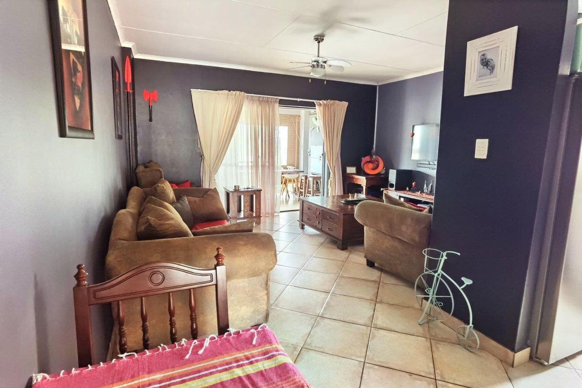 Spacious living room featuring tiled flooring, a ceiling fan, and sliding glass doors that provide access to an outdoor patio area.
