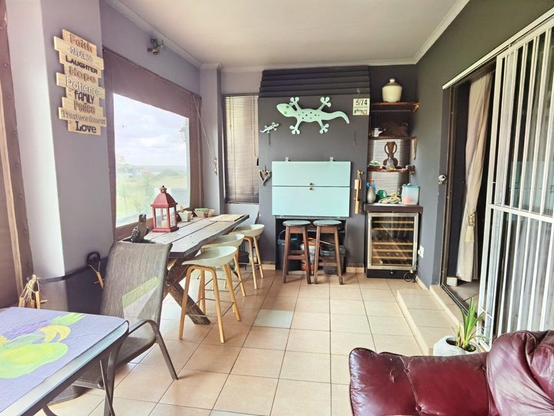 Covered patio area featuring tiled flooring, a built-in braai, and sliding door access to the main living space.