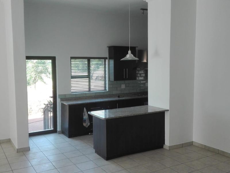 A clean, modern kitchen featuring dark cabinetry, granite countertops, and tiled flooring, with direct access to an outdoor area.