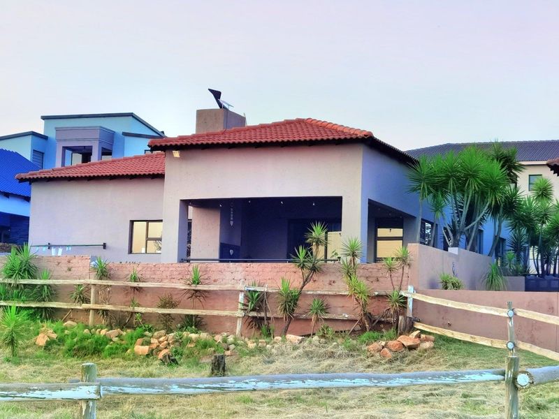 Rear view of the property featuring a covered patio, tiled roof, and a rustic timber fence enclosing the garden area.