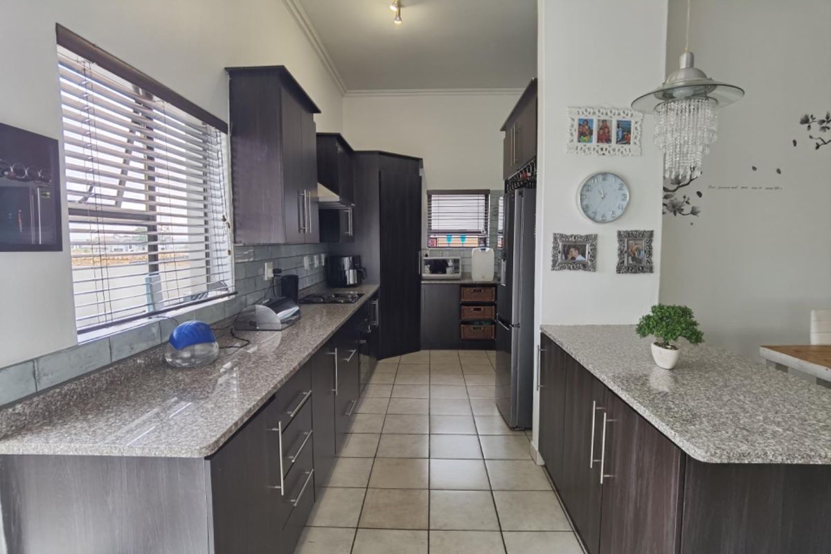 Modern kitchen featuring dark wood cabinetry, granite countertops, tiled flooring, and a functional layout with integrated appliances and ample storage space.