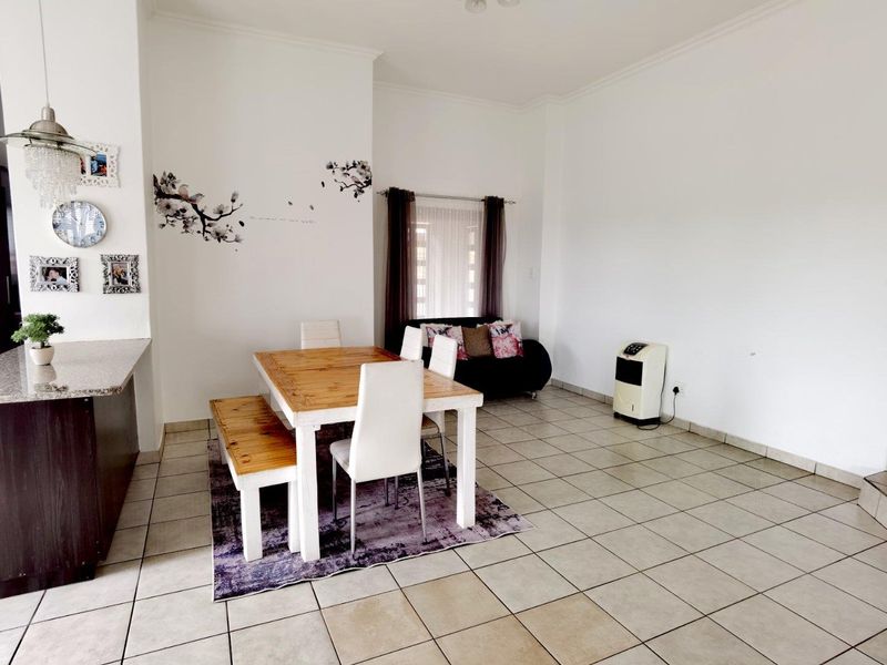 Open plan living and dining area featuring ceramic tiled flooring, coved cornicing, and a granite-topped kitchen breakfast bar.