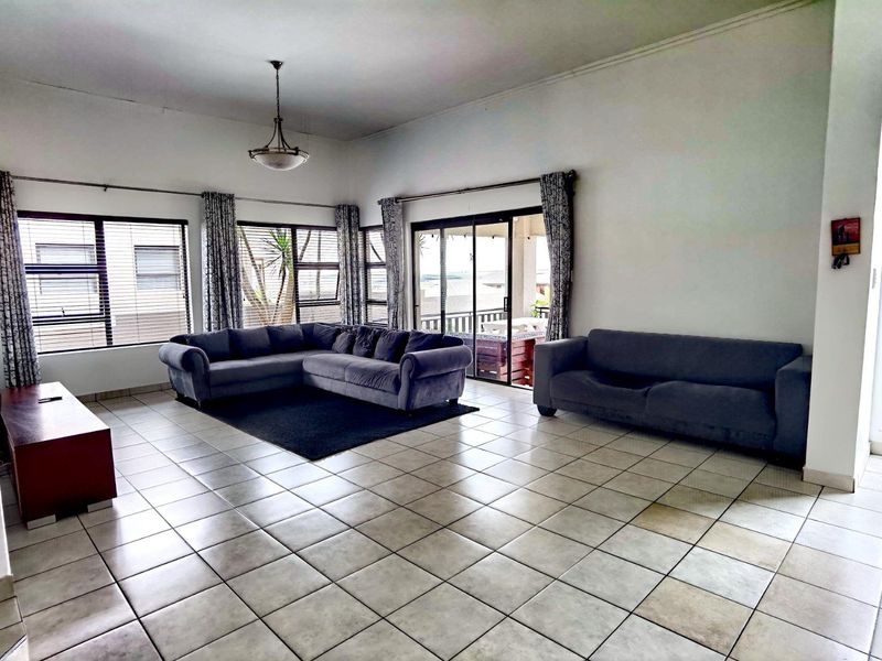 Spacious living room featuring large windows, tiled flooring, and sliding glass doors providing access to an outdoor patio area.