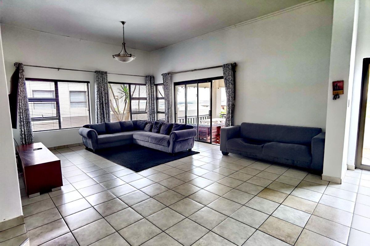 Spacious living room featuring large windows, tiled flooring, and sliding glass doors providing access to an outdoor patio area.