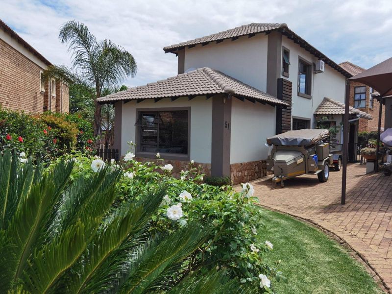 Front view of a two-story residential house featuring a tiled roof, stone cladding accents, and a well-maintained paved driveway and garden area.
