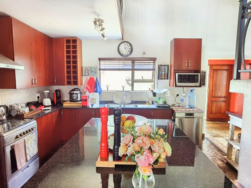 A functional kitchen featuring dark wood cabinetry, granite countertops, a central island, and integrated stainless steel appliances.