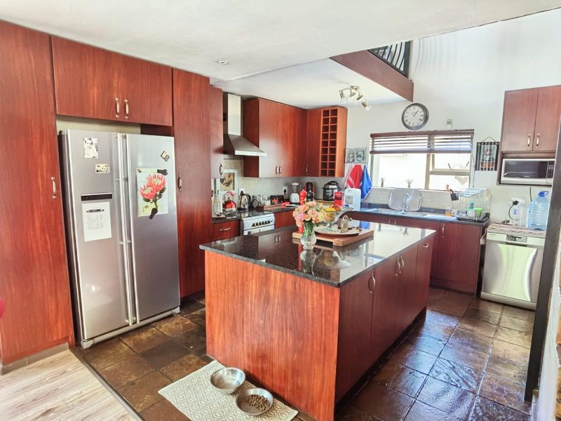 A functional kitchen featuring dark wood cabinetry, granite countertops, a central island, and tiled flooring, offering ample storage and workspace.