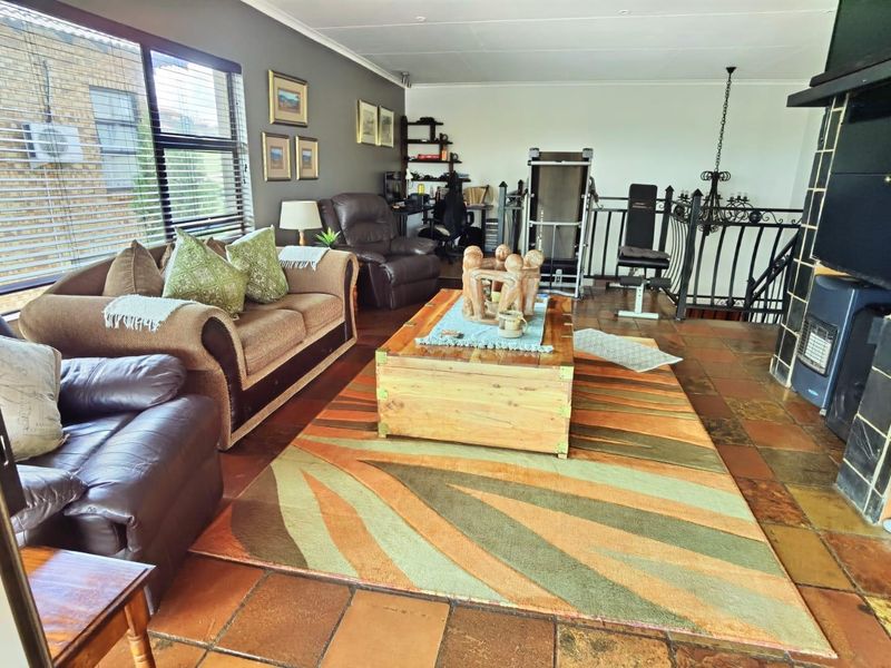 Spacious living room featuring terracotta-style tiled flooring, a built-in fireplace, and a wrought iron staircase railing leading to a lower level.