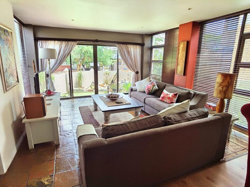 A sunlit living room featuring tiled flooring, large sliding glass doors leading to the garden, and integrated recessed lighting.
