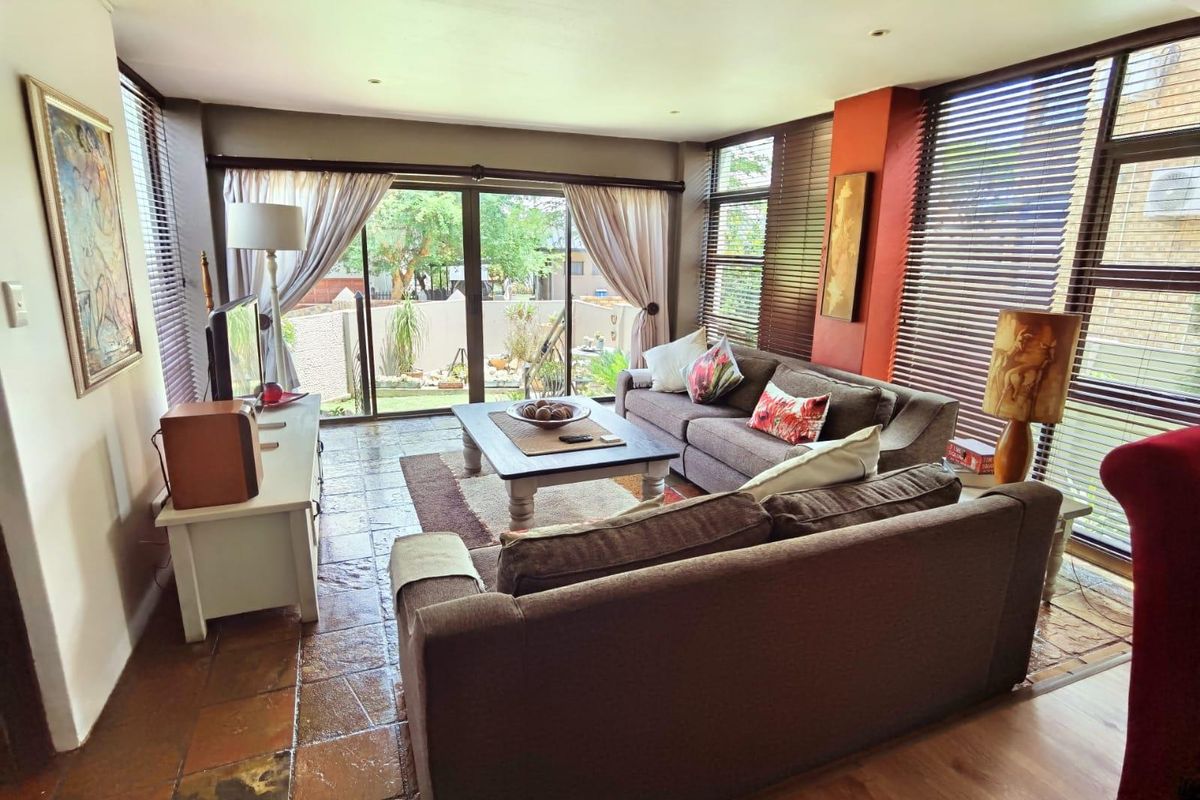 A sunlit living room featuring tiled flooring, large sliding glass doors leading to the garden, and integrated recessed lighting.