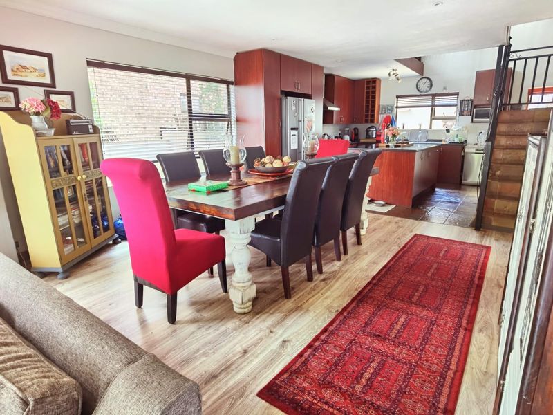 Open-plan living and dining area featuring laminate flooring and a functional kitchen with built-in cabinetry and a central island.