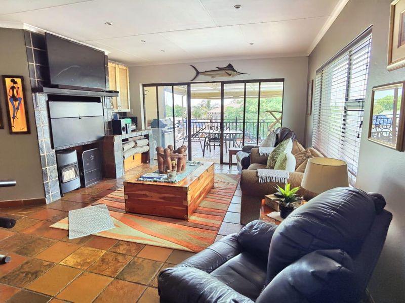Spacious living room featuring tiled flooring, a built-in fireplace, and large sliding glass doors providing access to the outdoor patio area.